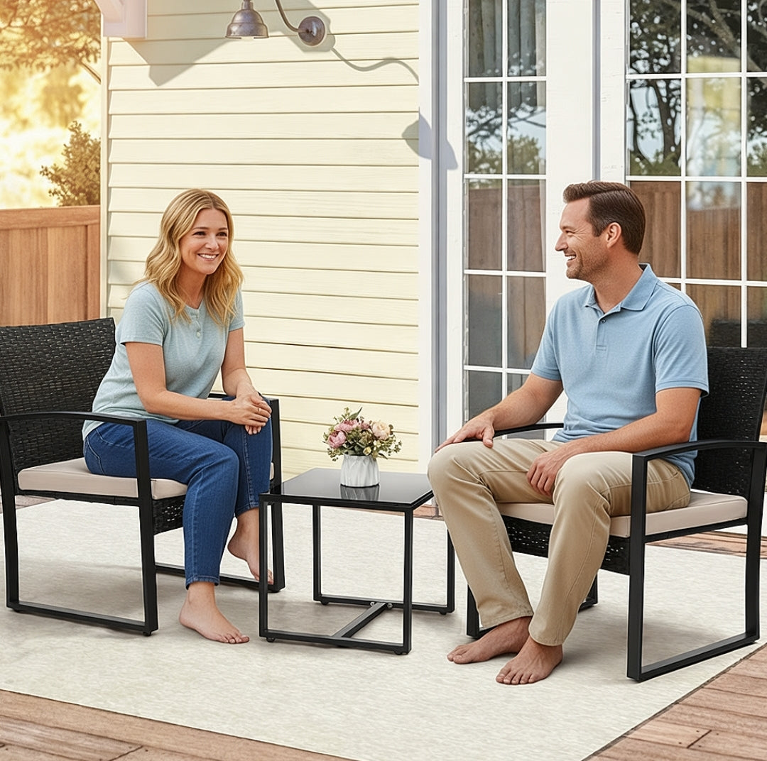 Man and woman sitting on outdoor patio furniture with a small table between them.